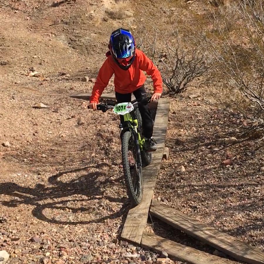 Mountain biking kid on wood skinny